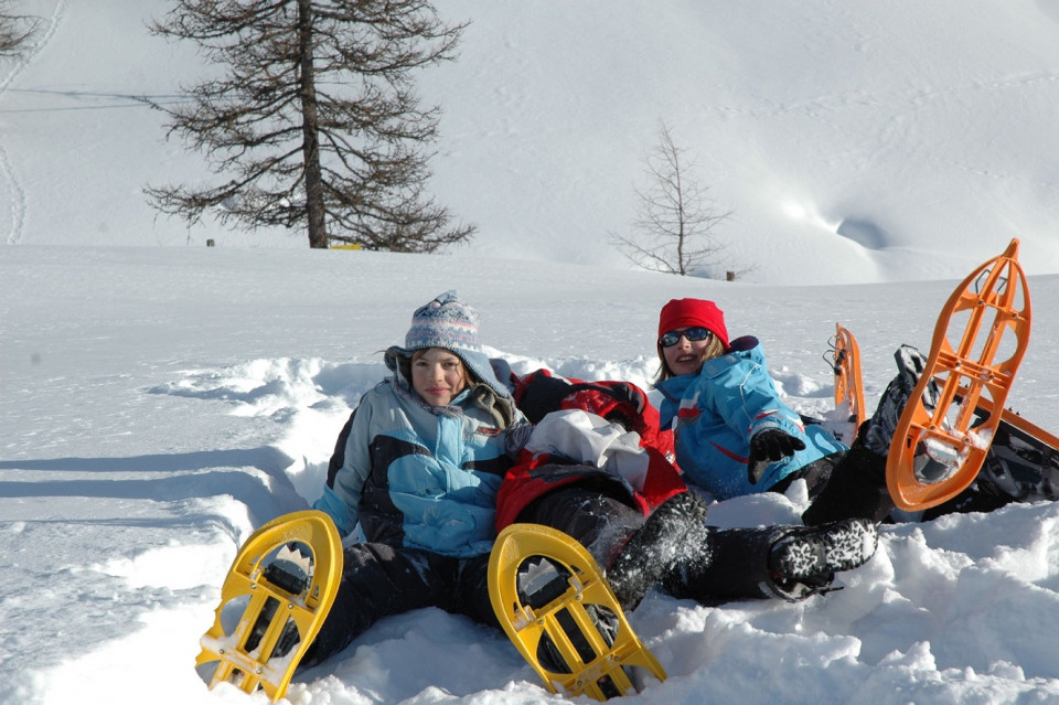 Kinder mit Schneeschuhen sitzen im Schnee